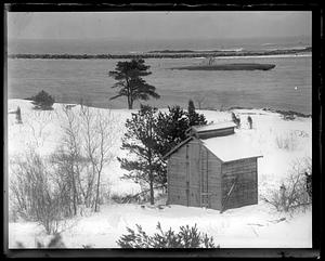 A wooden building by a body of water, USS S-48 going past