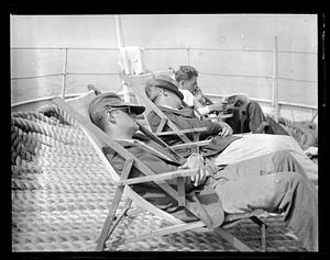 Men sleeping and reading a newspaper on top of ropes