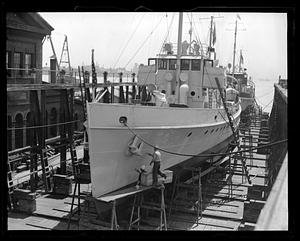 Workers painting the side of an unidentified ship in drydock