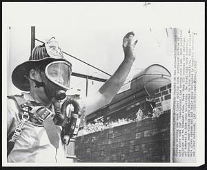 Diverts Traffic in Gas Area--Philadelphia fireman wearing gas mask direct traffic from northeast section of city where tank car (background) had broken pipe line that permitted chlorine gas to blanket the area. More than 275 persons were stricken and treated in five area hospitals. No fatalities were reported, although some victims were reported in poor condition. Most victims were given oxygen and had their eyes irrigated by hospital attendants and later released.