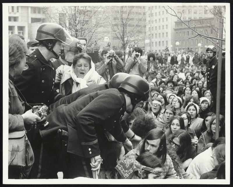 Women with strong expression is federal employee, escorted across crowd by police