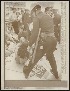 Policemen grapple with anti-war demonstrators blocking the sidewalk outside the hotel where President Johnson is scheduled to appear 6/23. The demonstrators suddenly dropped to the ground after milling about the area and police just suddenly began removing them. About 20 of the police pickets were arrested.