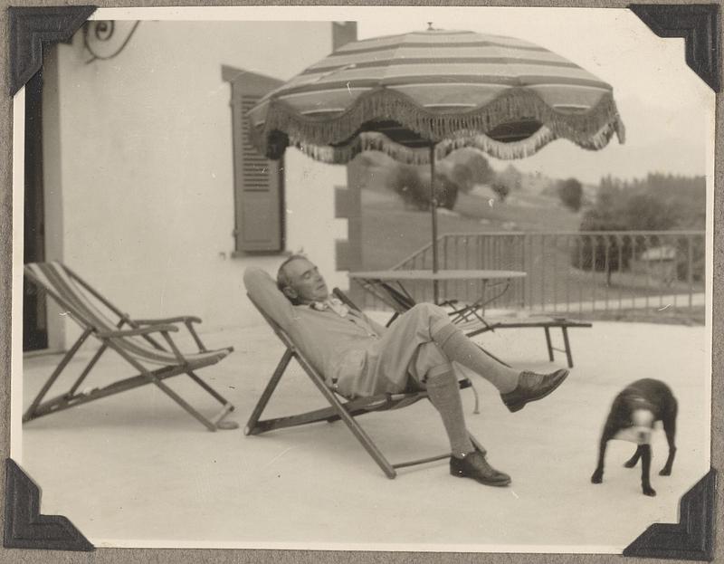 Serge Koussevitzky leans back in a chair, a Boston terrier at his feet