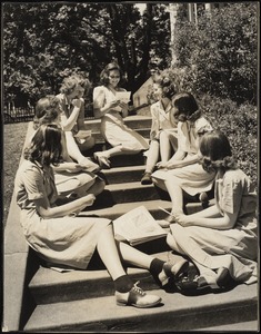 Seven students in uniform outside on steps with letters and newspaper