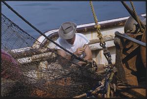 Man on boat working with net