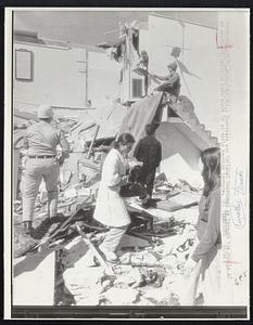 Survivors and National Guardsmen go through the rubble of an apartment building torn apart by an early morning tornado.