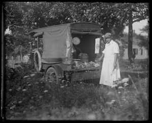 Old fashioned meat cart scale on base of Model T Ford. Man wearing apron