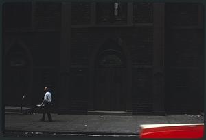 Man walking on sidewalk by Transfiguration Church, Manhattan, New York