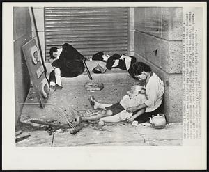 Doorway Shelter -- A mother and her small child and a policeman, still wearing his club, find shelter and rest in a doorway after an earthquake swept Fukui, Japan, June 28. The building, a cement and brick structure, was evidently one of few to withstand the quake. Photo by Charles Gorry, Associated Press Staff photographer.