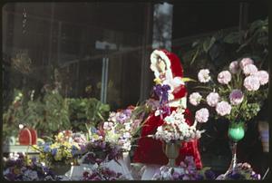 Flower arrangements next to a doll