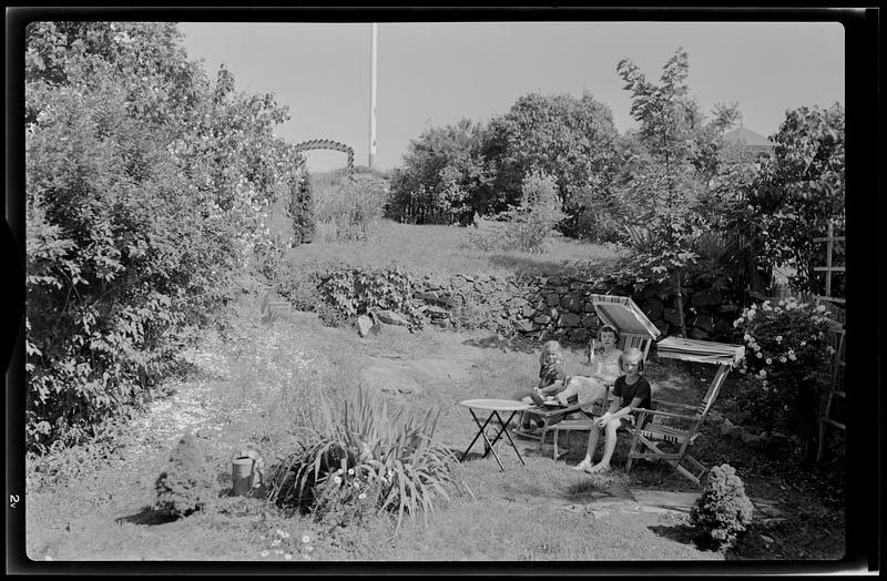 Two girls sitting in garden with woman