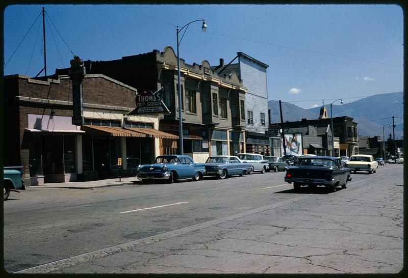 Small-town street with Thomas Dry Goods in setting with mountains, likely Montana