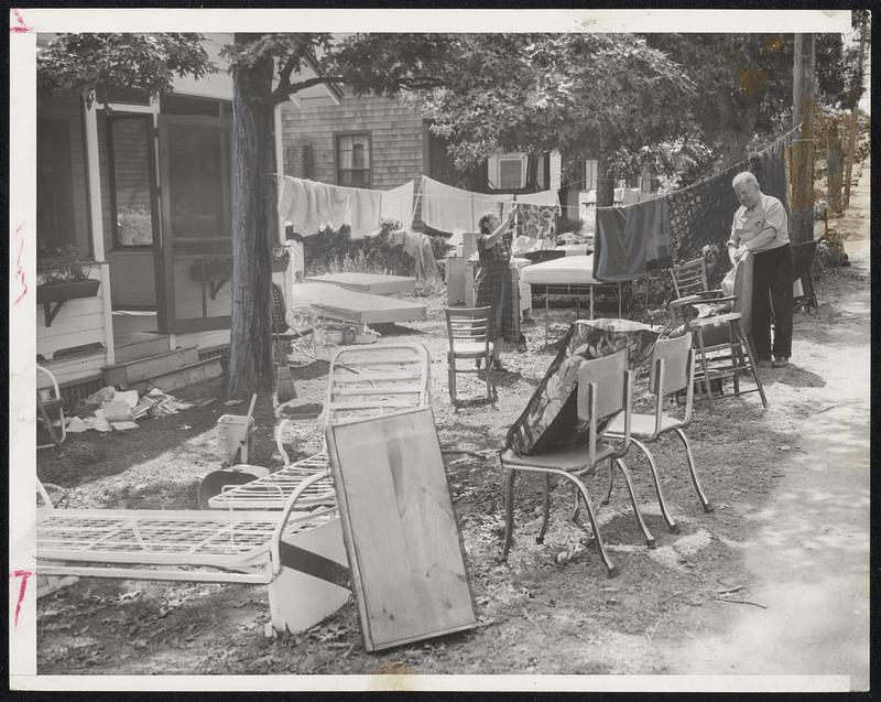 Fine Way to Treat Visitors-Southern visitors hit by Hurricane Carol dry out their belongings at their storm flooded cottage in Onset. The visitors are Mr. and Mrs. Louis Braverman of Miami Beach.