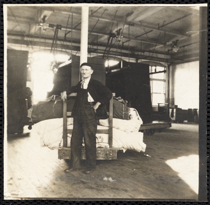 Textile mill worker with fabric loaded onto cart