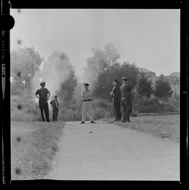 Police standing near brush fire at Brighton High School during demonstration