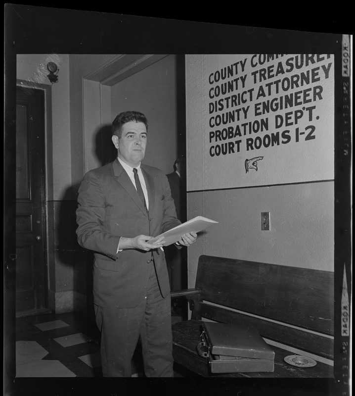 Assistant District Attorney Donald Conn with folio in front of directional signage at the courthouse