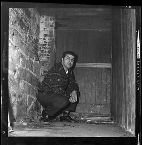 Man kneeling in a passageway by a wooden door
