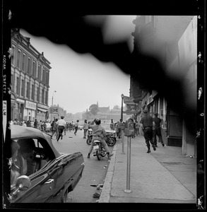 Street scene with a police officer on a motorcycle and students running