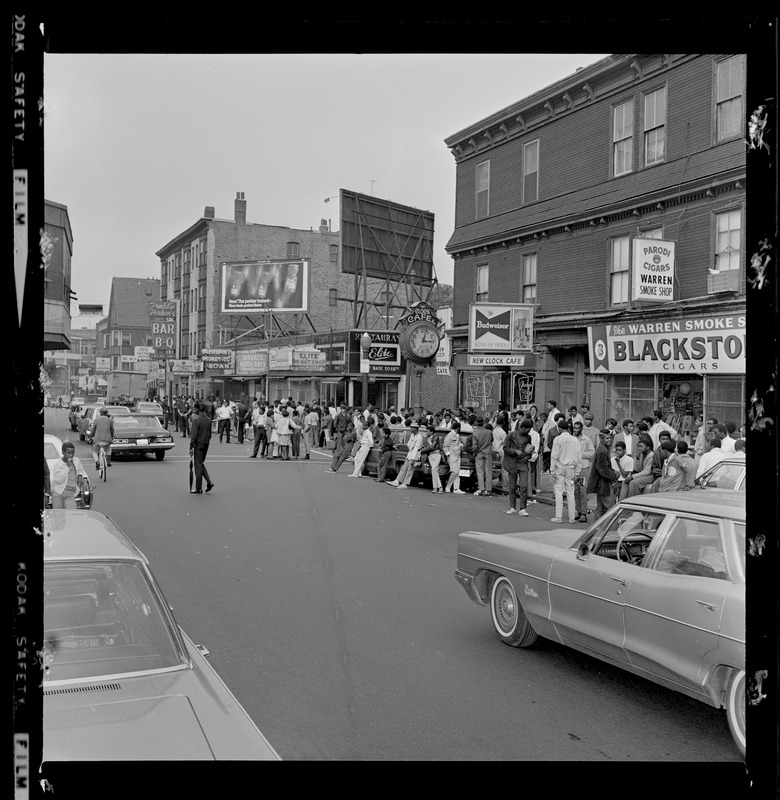 Group of people on side of street watching traffic move