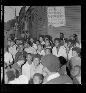Large gathering of people in front of Dudley Door Window and Lumber Co. sign