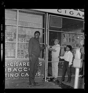 Smoke shop owners passing cigarettes through gate after locking storefront