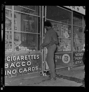 Man handing smoke shop owner money through gate