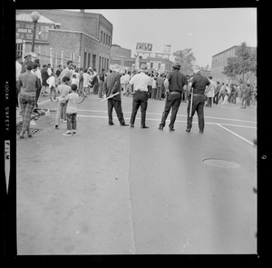 Four police officers stand across from the gathering crowds