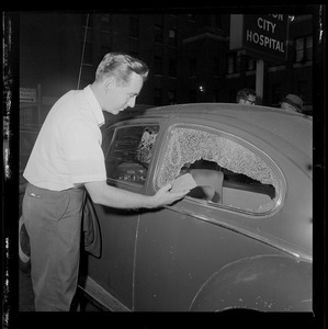 James Devereaux surveys the damage to his vehicle that was smashed by a brick on the corner of Harrison Avenue and Dudley Street in Roxbury