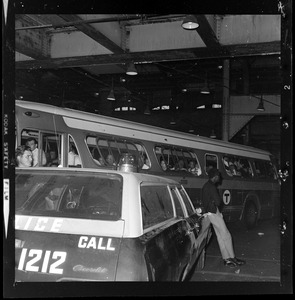 Man leaning on police car as an MBTA bus goes by