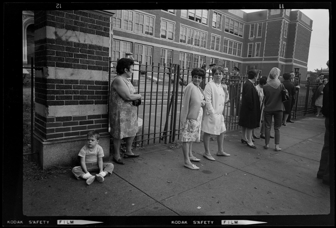 Women standing outside the gates of East Boston School