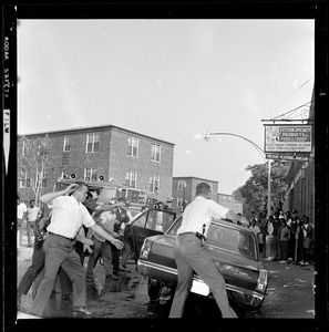 Officers and firemen around a car with their hands in the air