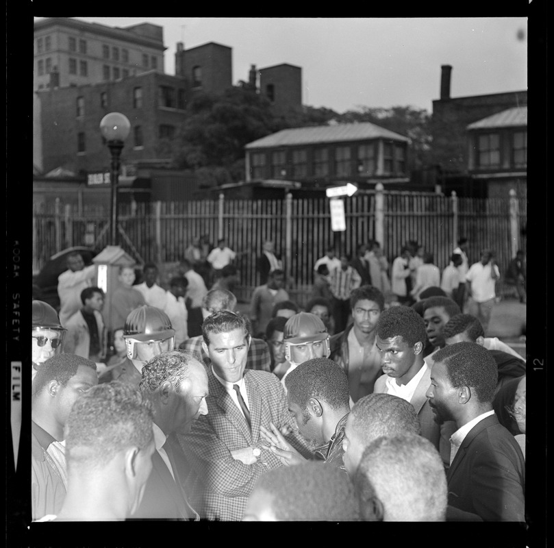 People gathered, including police, and having a discussion on the street