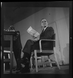 Kevin White seated, holding notes, during the debate