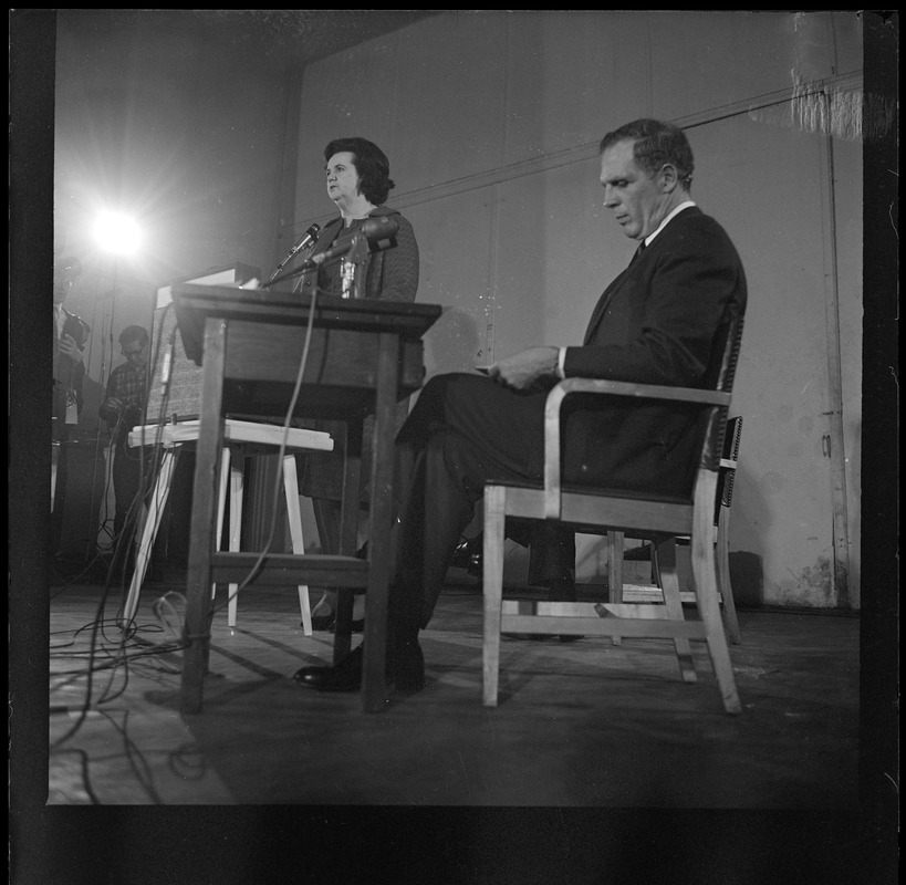 Louise Day Hicks addresses the room during the debate as Kevin White looks at his notes