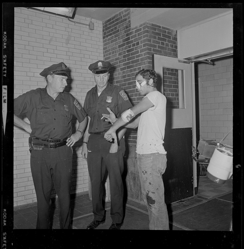 Construction worker Kenneth Kurker, 26, of Arlington, shows policeman his slashed arm and face injuries