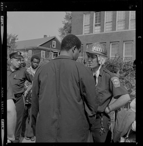 Man talking with police officer wearing a riot gear helmet