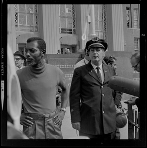 Unidentified Black man standing next to police captain in front of Jeremiah E. Burke High School, most likely during unrest that broke out after student demonstrations