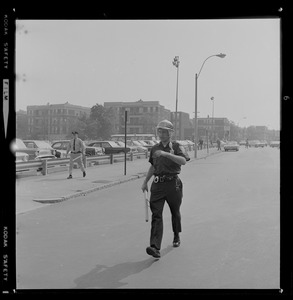 Police officer wearing riot gear helmet walking down the street