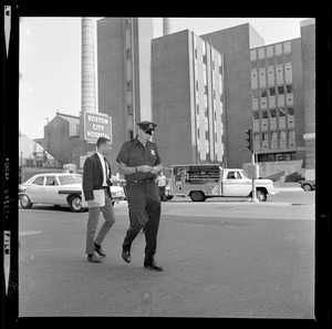 Police officer walking across the street from Boston City Hospital