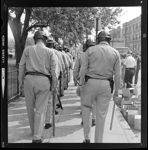 Two lines of police in riot gear lined up on the sidewalk