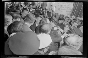 Hubert Humphrey walking through a crowd with people holding anti-Nixon and Lyndon Johnson posters