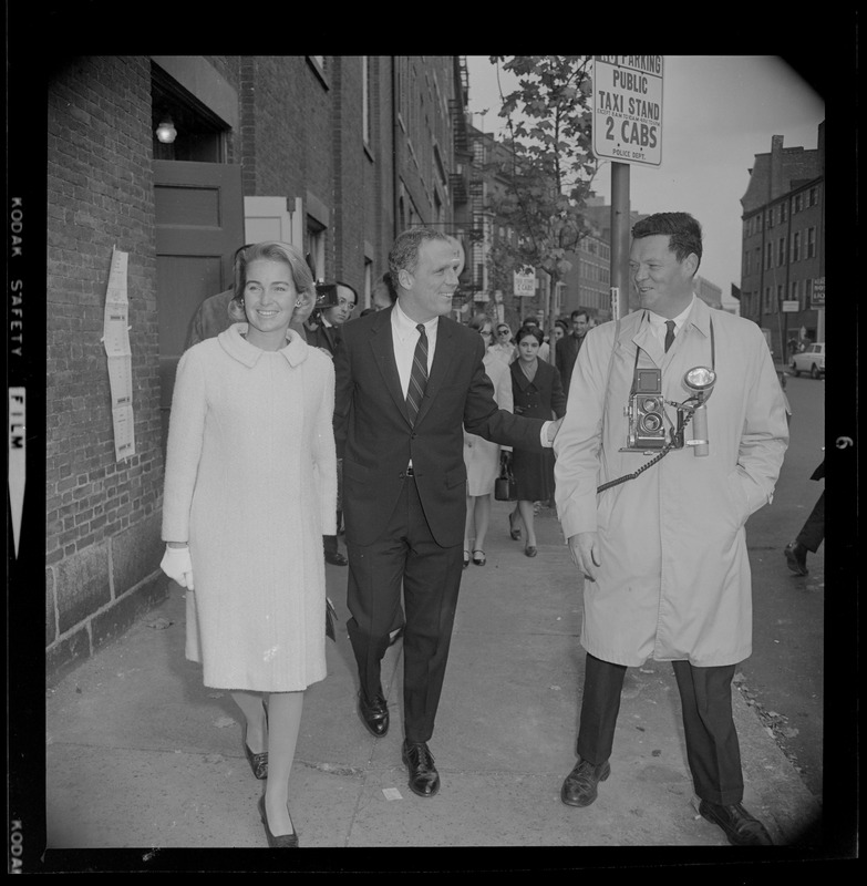 Kevin White and wife walking down the sidewalk and greeting a photographer