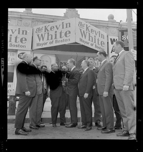 Kevin White meets with a large group of men outside "Elect Kevin White" posters