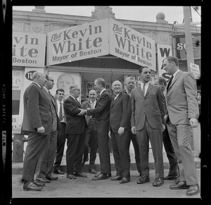Kevin White meets with a large group of men outside "Elect Kevin White" posters