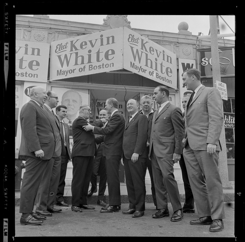 Kevin White meets with a large group of men outside "Elect Kevin White" posters