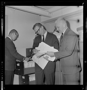 Secretary of State Kevin H. White (center) with Norman Gleason (left), supervisor of elections in White's office, and James Kane, supervisor of financial records of political candidates, check over a few of the thousands of campaign contribution reports
