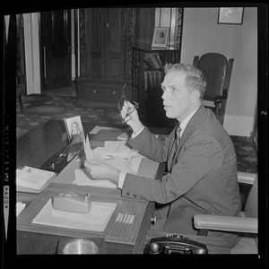 Secretary of State Kevin H. White sitting at desk and going over election charts for the governor race