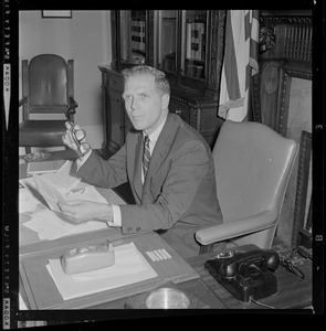 Secretary of State Kevin H. White sitting at desk and going over election charts for the governor race
