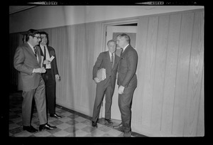 Mayor Kevin White walks out of a room and joins three other men in a hallway, including his Press Secretary Richard Flavin, left