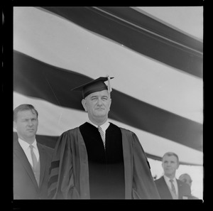 President Johnson in cap and gown on stage at Holy Cross College commencement